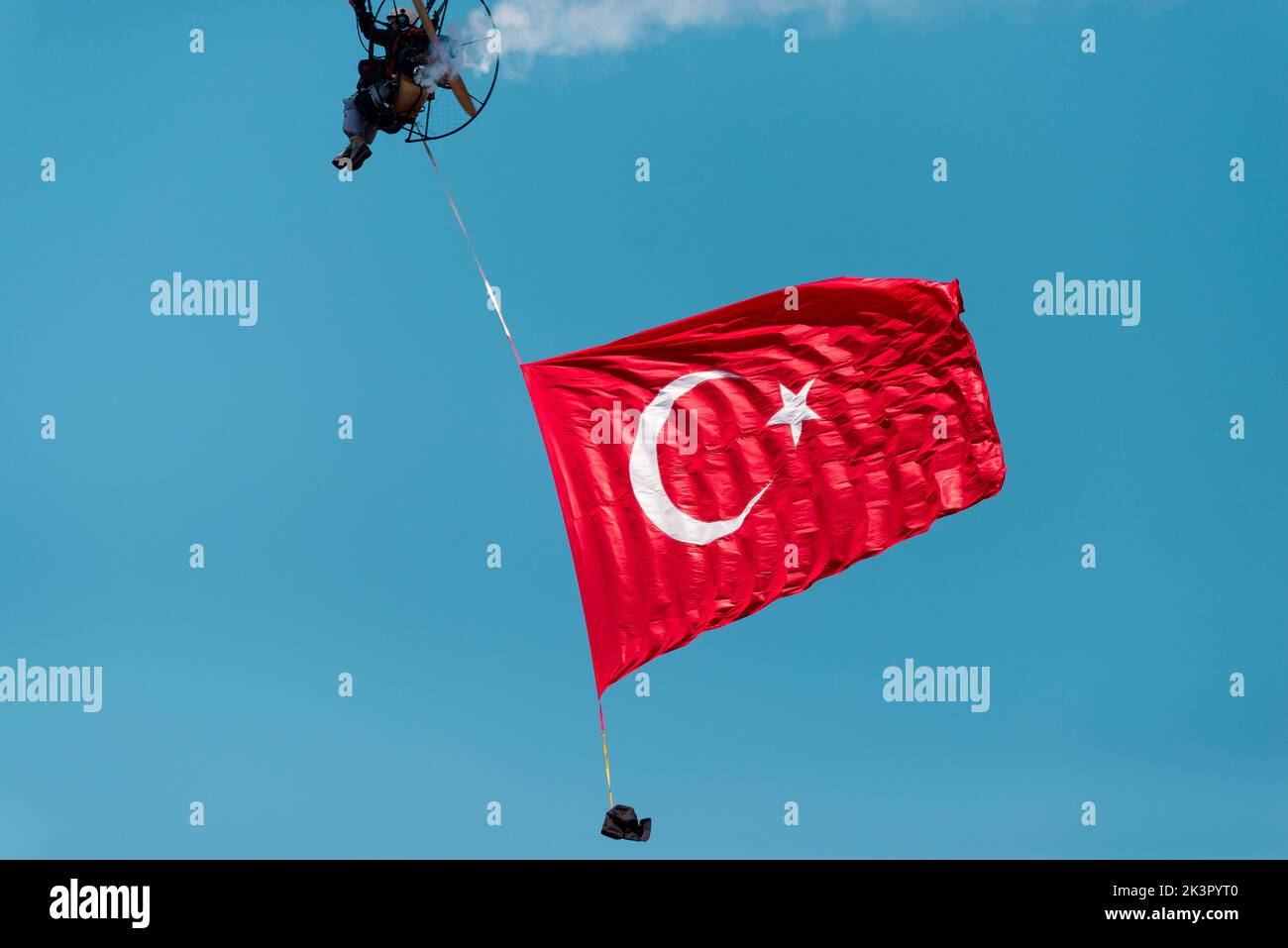 Izmir, Türkei - 9. September 2022: Paramotorspringer am Himmel mit einer riesigen türkischen Flagge am Tag der Freiheit von Izmir in Izmir Konak Türkei Stockfoto