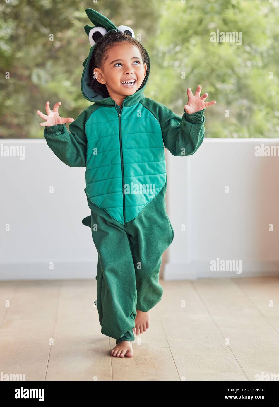 Kind, Lächeln und aufgeregt in halloween Dinosaurier Kostüm zu Hause spielen Rolle und Spaß auf der Party. Glückliches Kind, das mit Fantasy-Charakter verspielt ist Stockfoto
