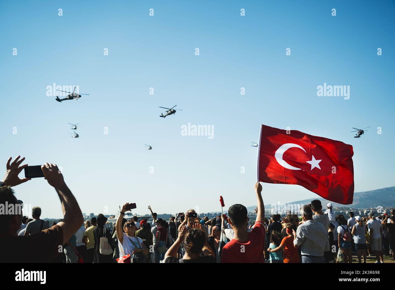 Izmir, Türkei - 9. September 2022: Nahaufnahme einer türkischen Flagge in den überfüllten Menschen mit Gendarm-Hubschraubern am Himmel am Tag der Freiheit von I Stockfoto