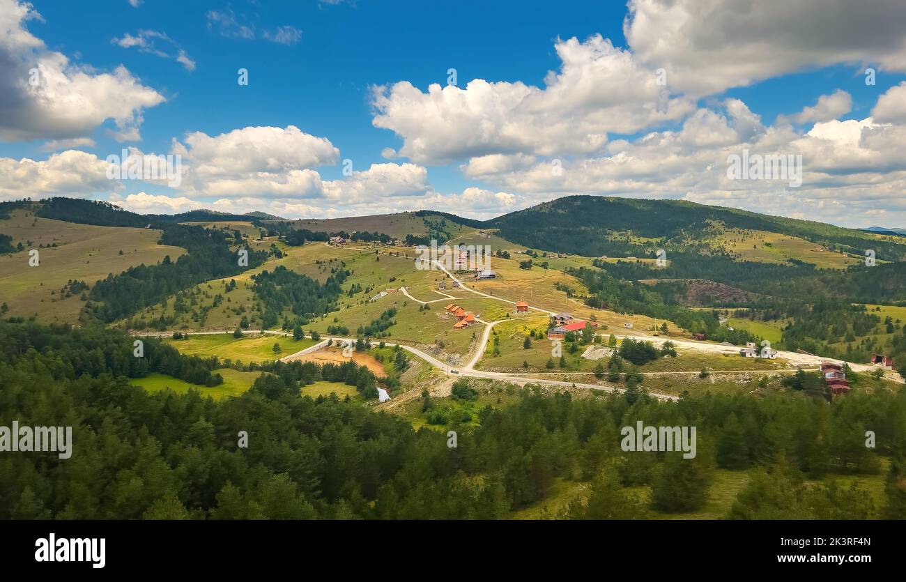 Schöne Landschaft Zlatibor mit Häusern, die an sonnigen Sommertagen über grüne Hügel verstreut sind, von der Seilbahn aus gesehen Stockfoto