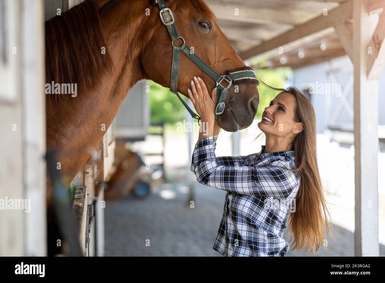 Junge Frau in einem Stall mit ihrem Pferd Stockfoto