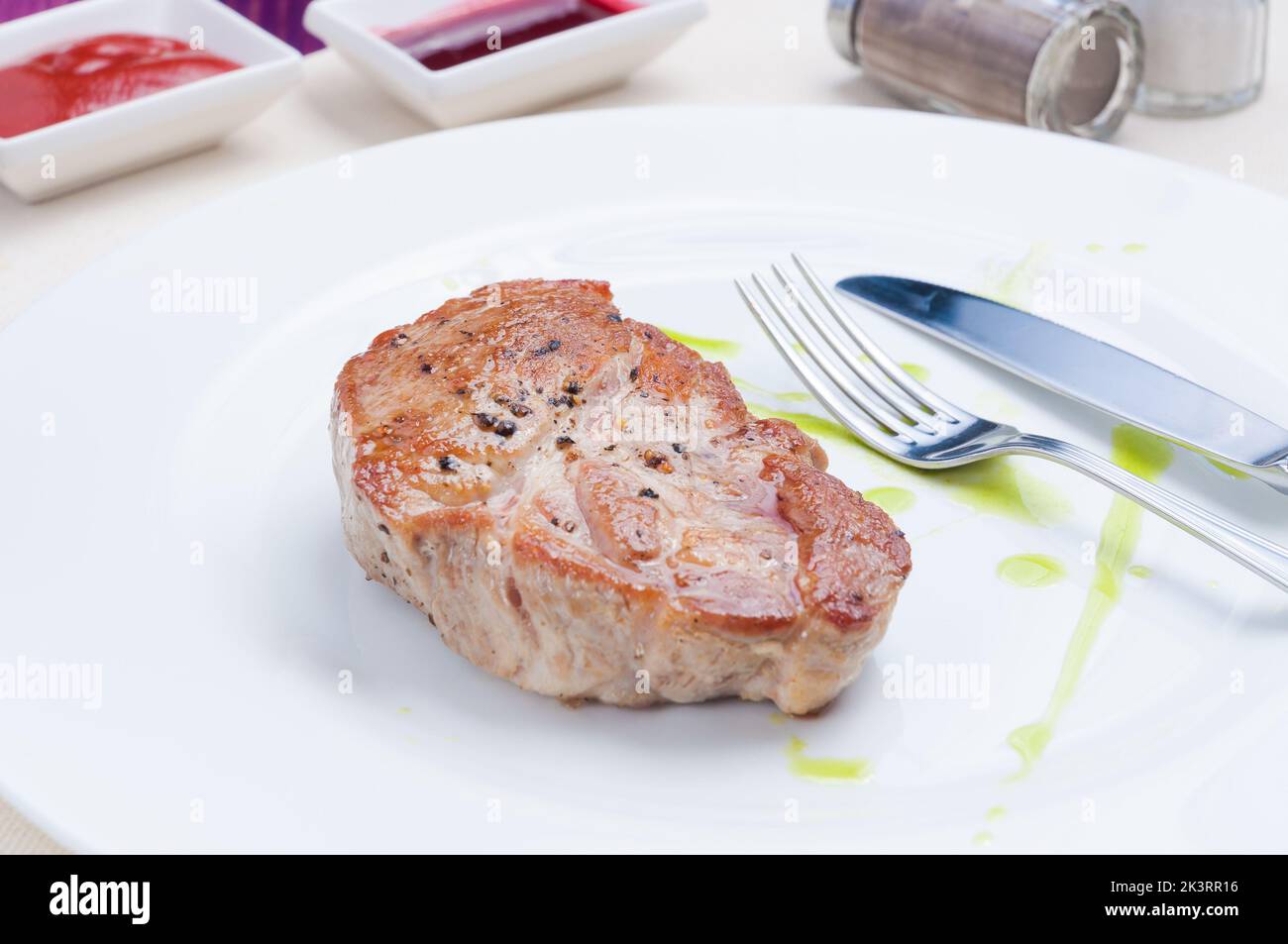 Leckeres saftiges Schweinesteak auf einem weißen Teller Stockfoto