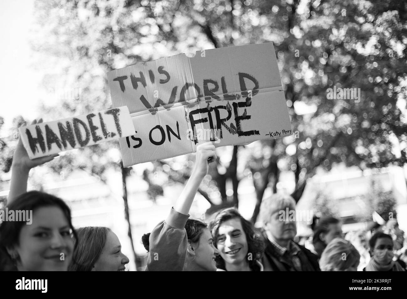 Teilnehmer*innen mit Schildern 'handelt' und 'Diese Welt brennt'. Am 23.9.2022 sammeln sich in München bis zu 10,000 Menschen, um gemeinsam mit Fridays for future auf dem globalen Klimabereich für Klimagerechtigkeit, den Ausbau der dezentralen erneuerbaren Energien, kostengünstigen ÖPNV und für ein 100 Mrd. Euro Sondervermögen für gerechte Klimaschutzmaßnahmen und Krisenprävention zu demontieren. Das Motto des Großstreiks war wieder People Not Profit. -- Teilnehmer mit Zeichen "handelt" und "diese Welt brennt". Am 23. September 2022 versammelten sich bis zu 10.000 Personen in München, Deutschland, um Stockfoto