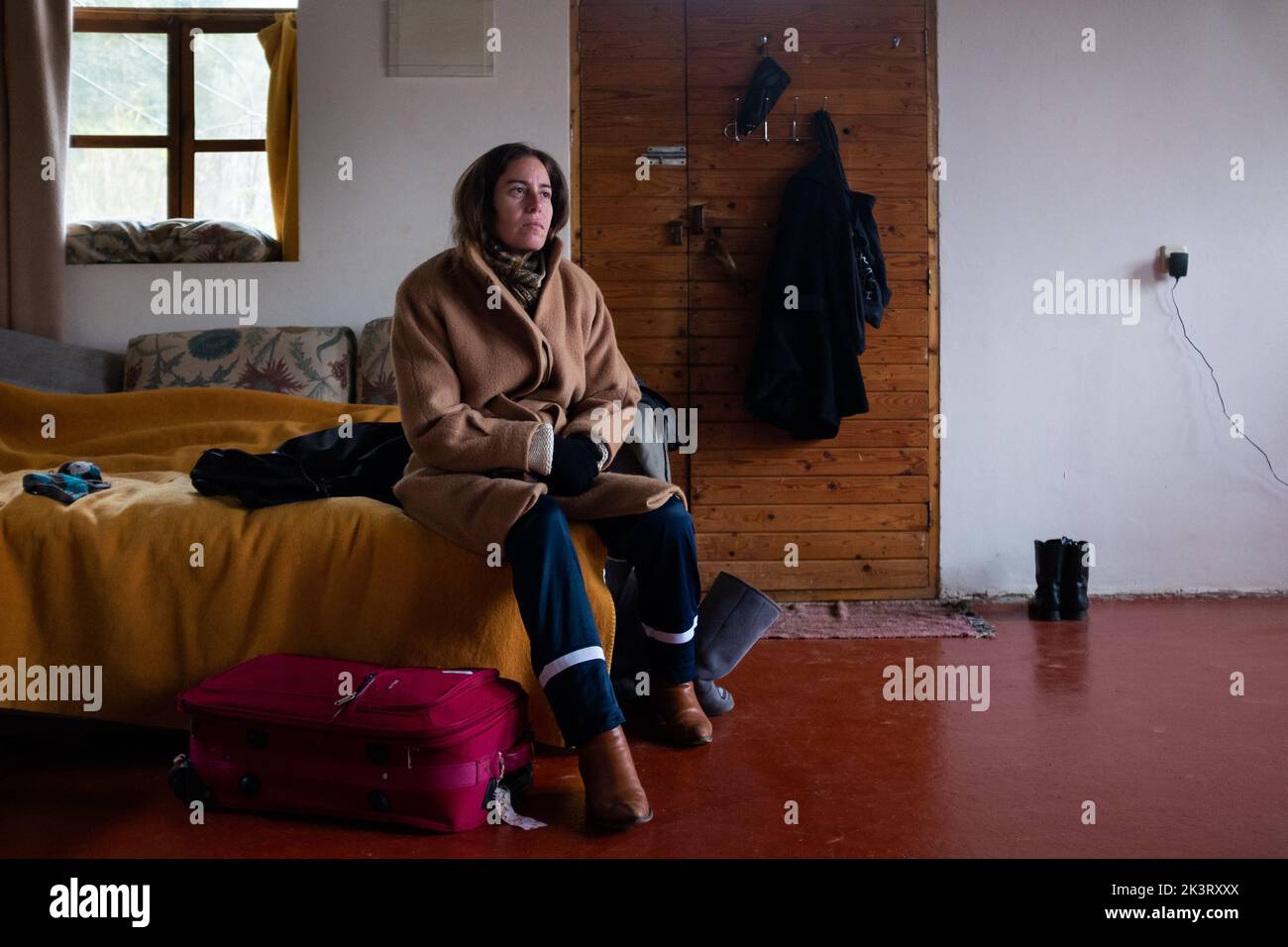 Frau mit Wintermantel sitzt auf einem Schlafsofa in der Kabine, während sie sich auf das Ausgehen vorbereitet Stockfoto