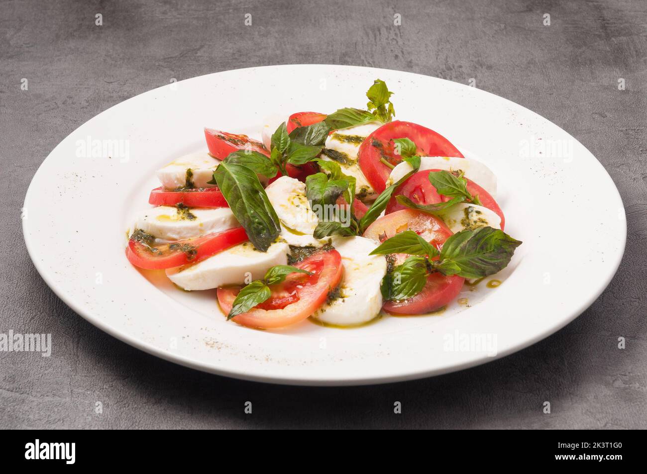 Leckerer Caprese-Salat mit Tomaten und Mozzarella auf einem weißen Teller Stockfoto