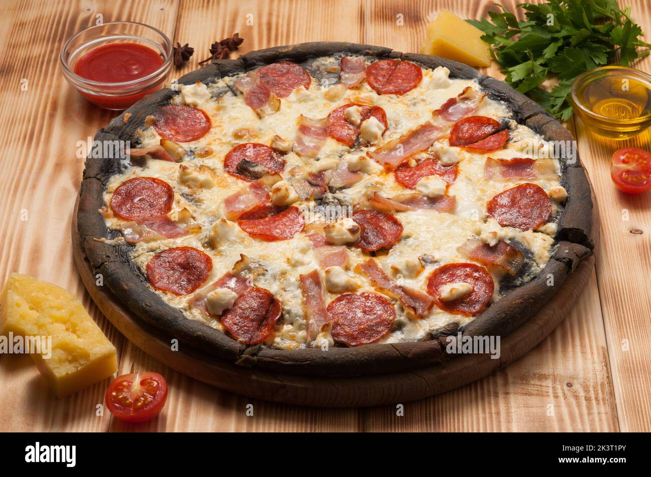Leckere Pizza mit Pepperoni, Speck und Mozzarella auf dem Teig schwarz Stockfoto