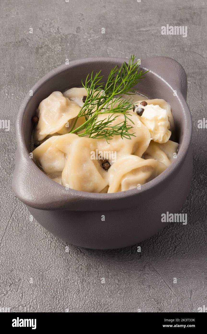 Leckere Knödel in einem Topf in Brühe mit Butter und schwarzem Pfeffer Stockfoto