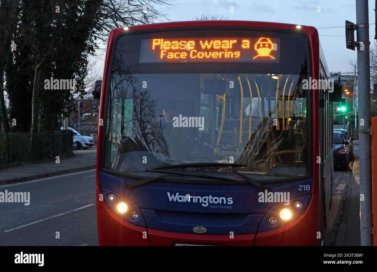 Öffentlicher Bus von Warrington mit Schild zu Bitte tragen Sie eine Gesichtsbedeckung, um sich vor der Wintergrippe und Covid19 Coronavirus-Infektionen zu schützen, Keshire, Großbritannien Stockfoto