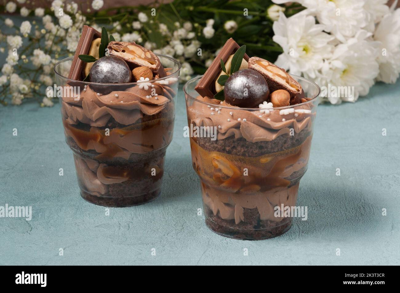 Süße Desserts in Plastikbechern mit Creme und Schokolade Stockfoto