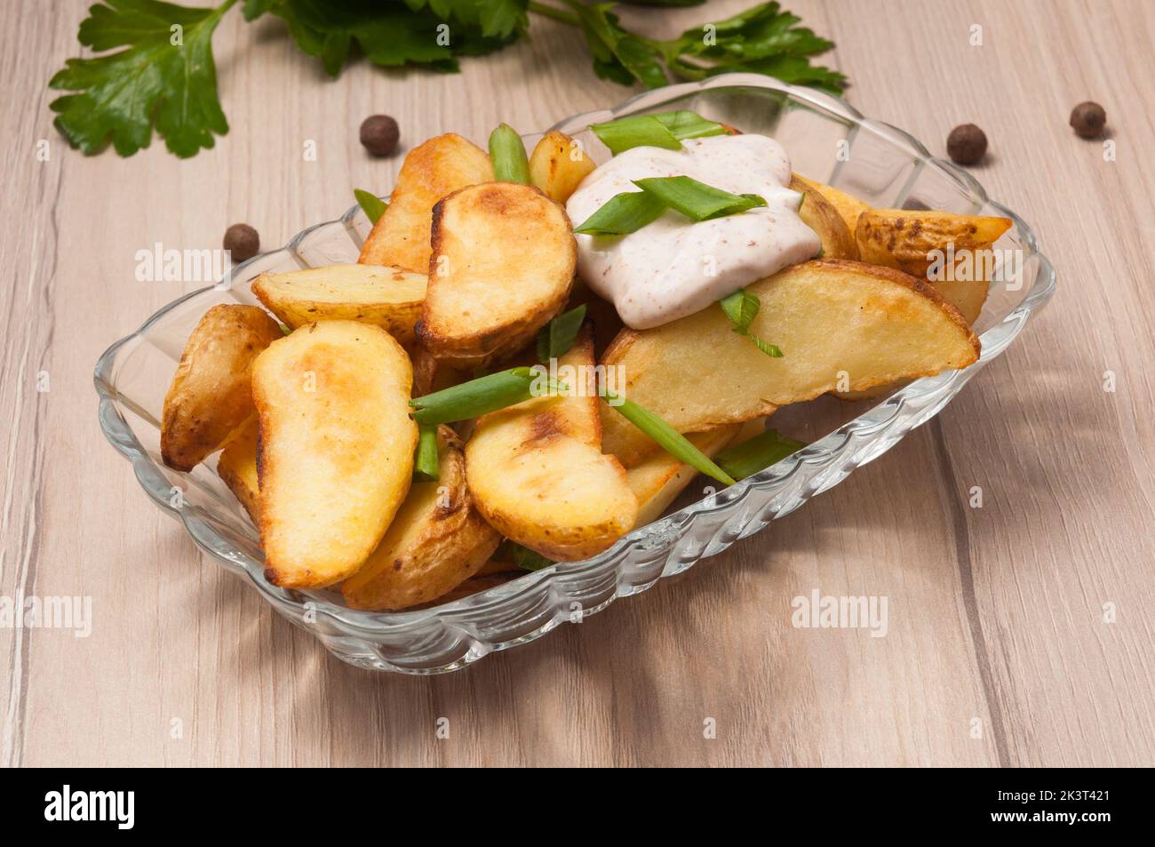 Leckere Kartoffelscheiben im rustikalen Stil mit saurer Rahm und grünen Zwiebeln Stockfoto