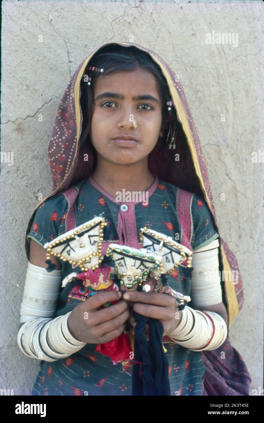 Junge Frau mit Puppen in der Hand aus Kutch mit besticktem und verspiegeltem farbenfrohem Kleid, Gujrat, Indien Stockfoto