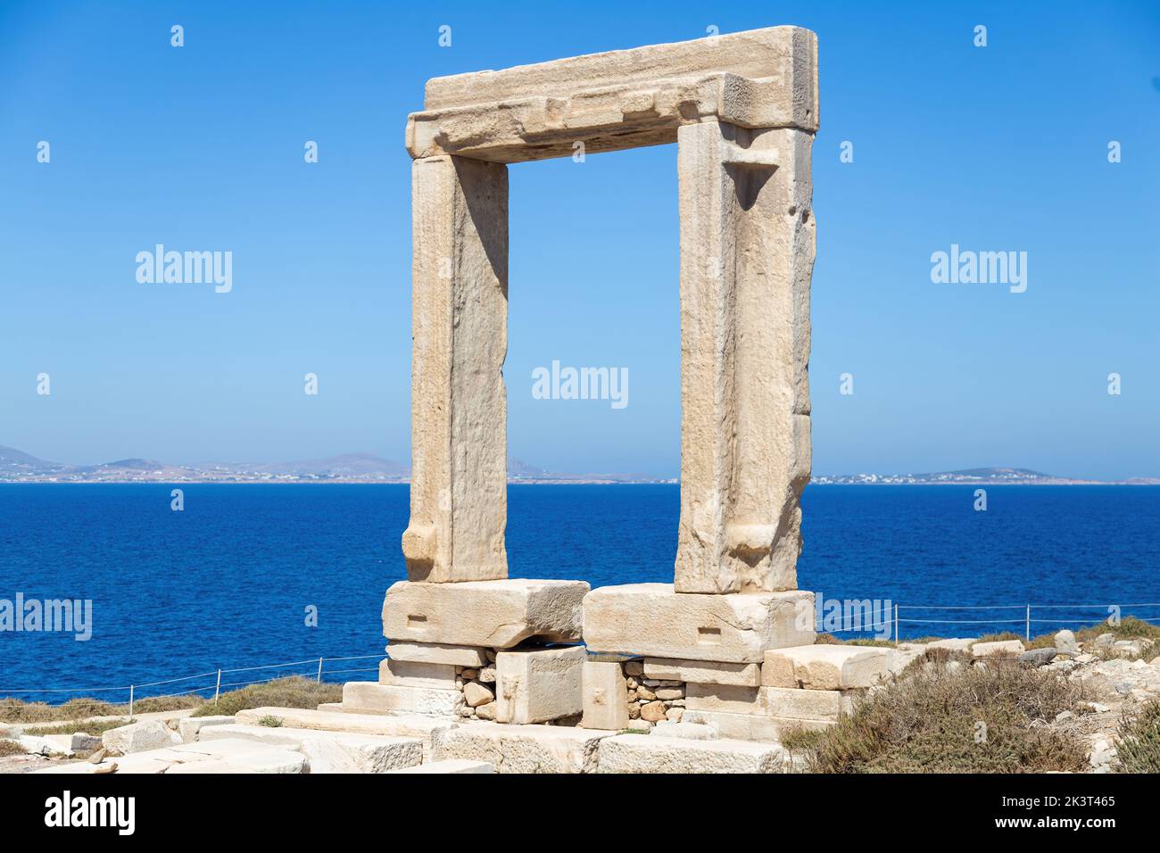 Insel Naxos, Apollotempel, Kykladen Griechenland. Portara, Marmortor, sonniger Tag, ruhiges Meer, blauer Himmel im Hintergrund. Stockfoto
