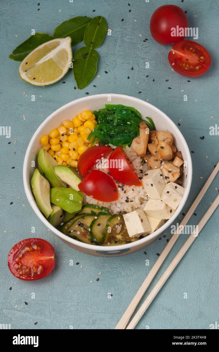 Schmackhafter vegetarischer Poke mit Avocado, Pilzen, Mais, chuka, Tofu-Käse, Gurken und Kirschtomaten Stockfoto