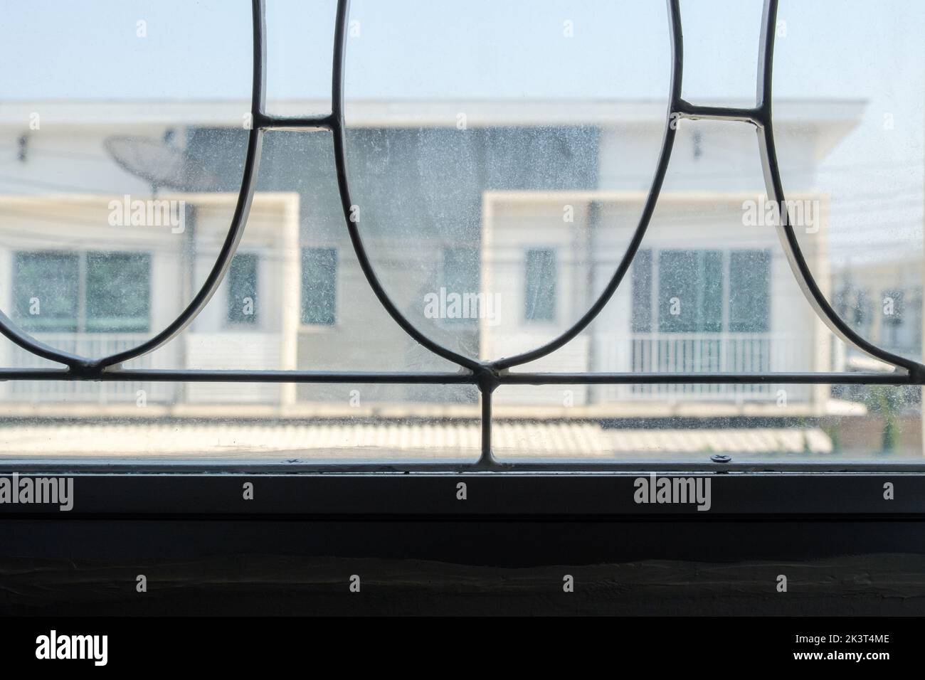 Nahaufnahme aus weiß lackiertem Schmiedeeisen durch das Buntfenster zum städtischen Dorf, Vorderansicht mit dem Kopierraum. Stockfoto