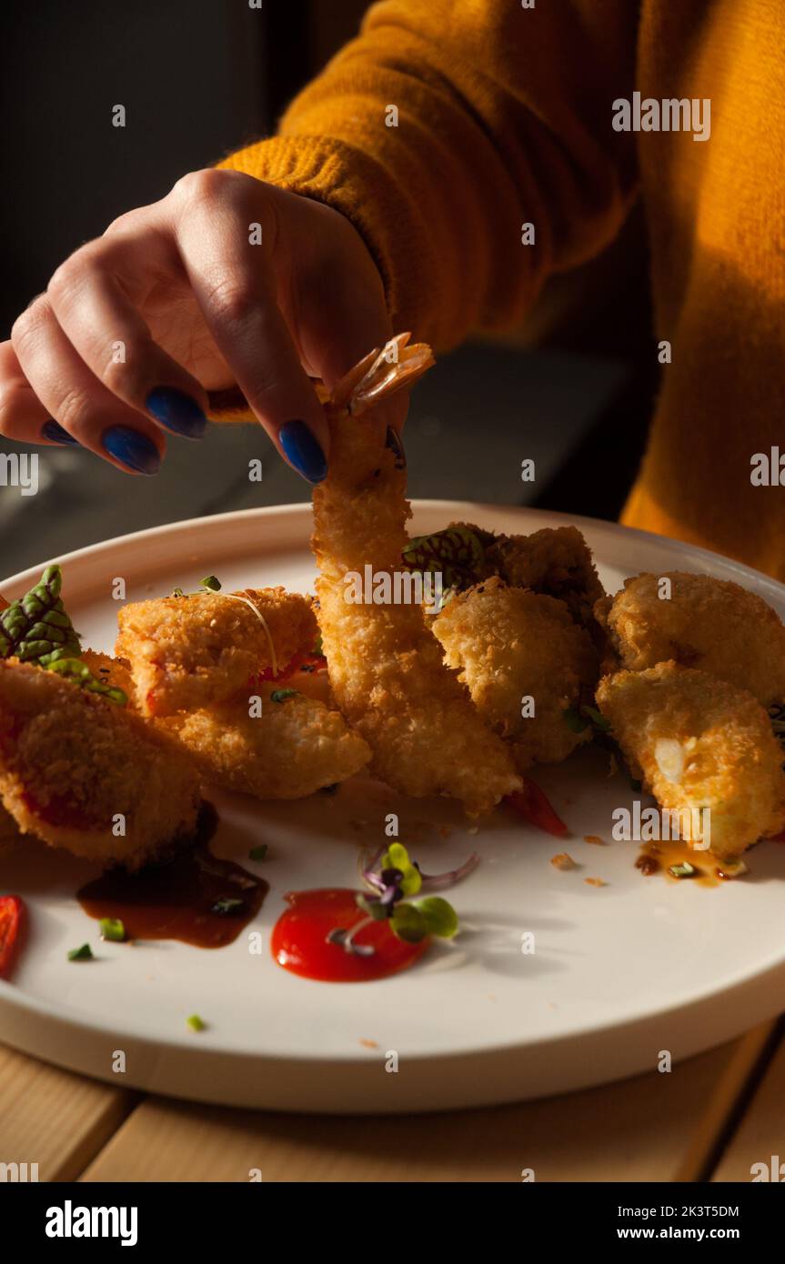 Frau, die in einem Restaurant frittierte Garnelen isst Stockfoto