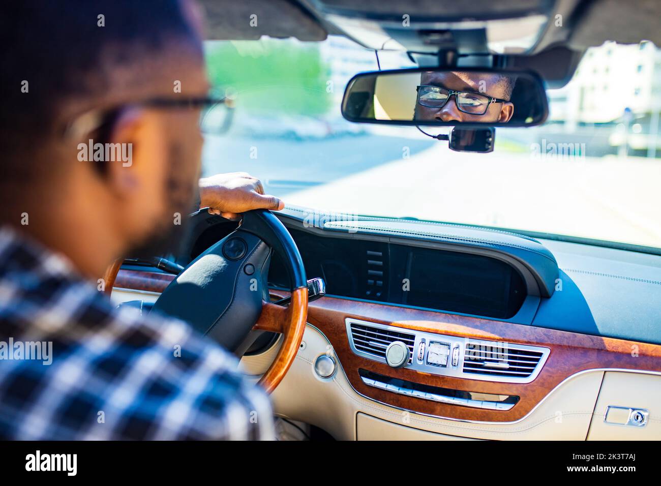 afroamerikanischer Mann, der in einem Auto sitzt und den Rückspiegel nach hinten anpasst Stockfoto