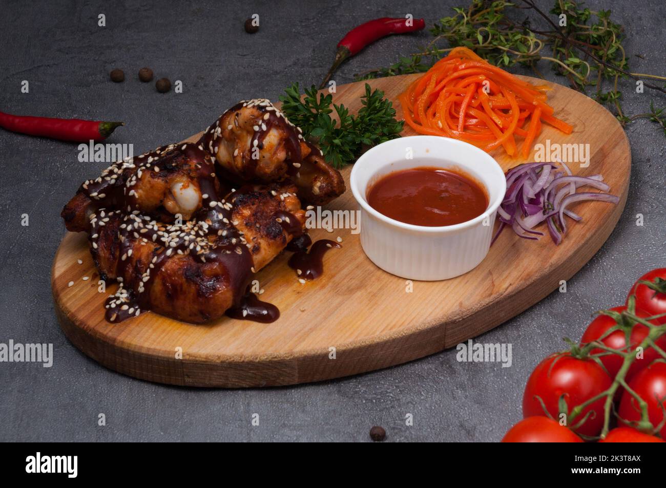 Leckere Hähnchenflügel mit Tomatensauce auf einem Holzbrett Stockfoto