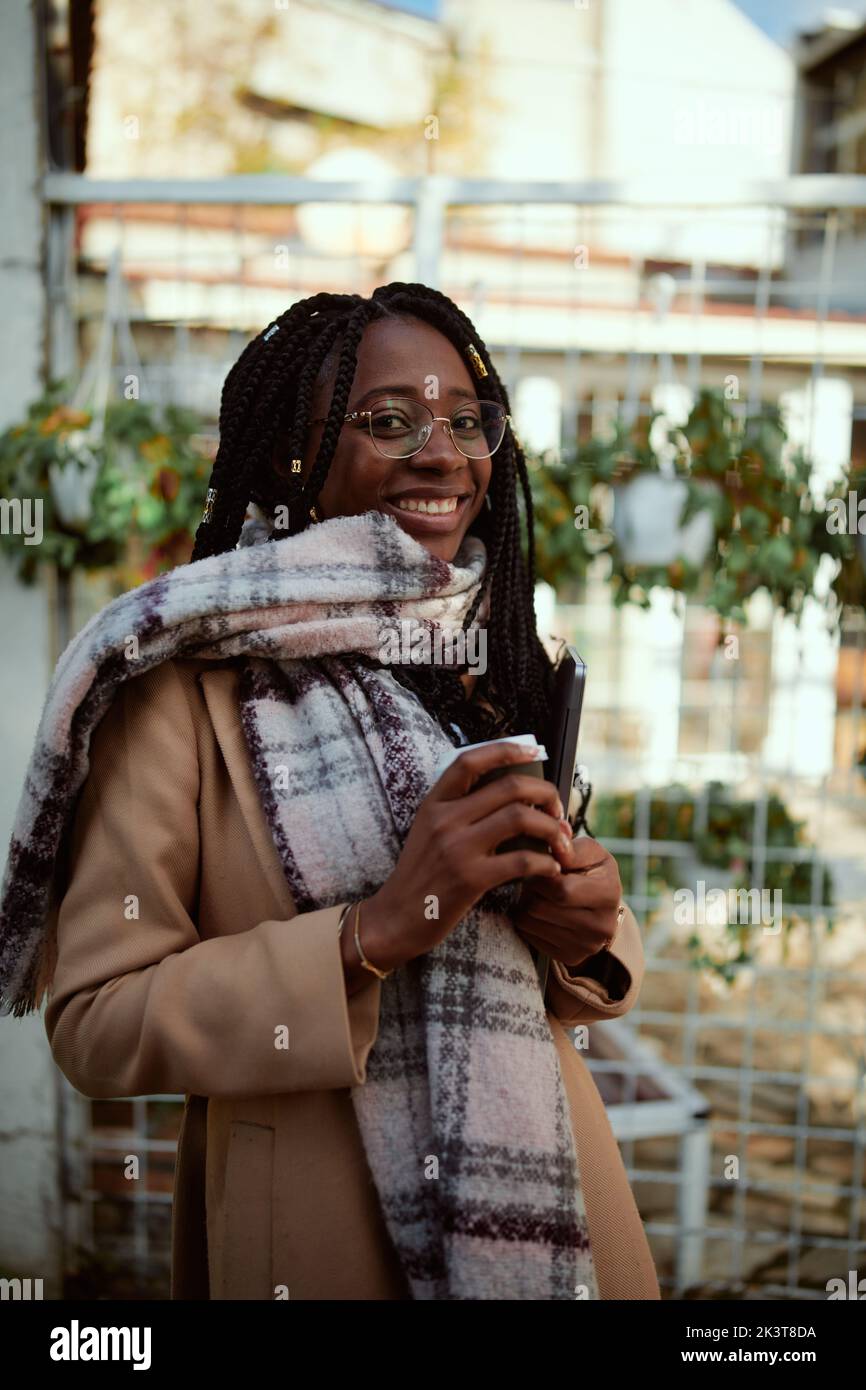 Eine glückliche afrikanische Unternehmerin steht draußen mit einem Laptop in den Händen. Stockfoto