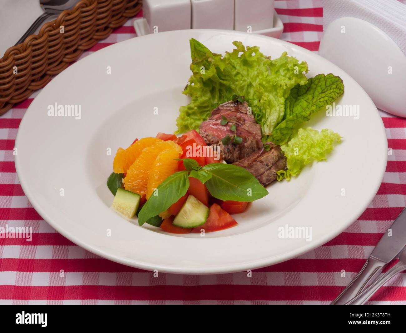 Leckerer Salat mit Gemüse, Rindfleisch und Orange auf einem weißen Teller Stockfoto