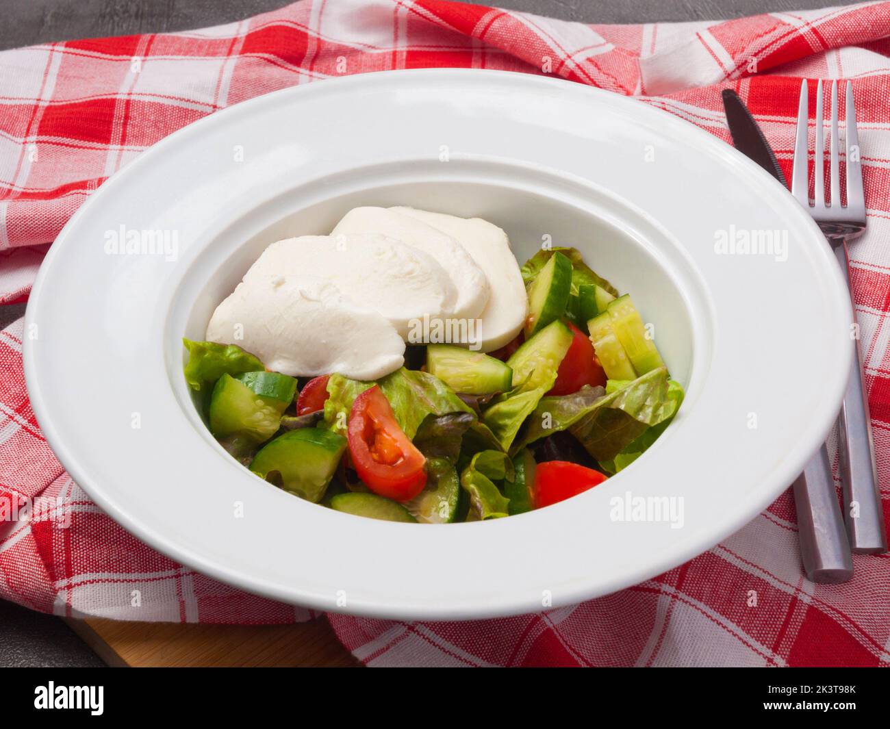 Leckerer Salat mit Gemüse und Mozzarella auf einem weißen Teller Stockfoto