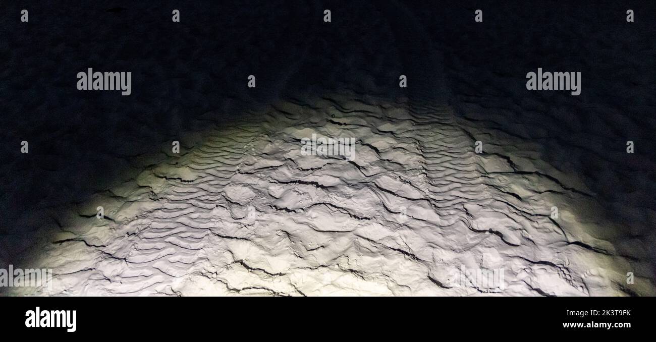 Blitzlicht beleuchtet Spuren im Sand in der Nacht Stockfoto