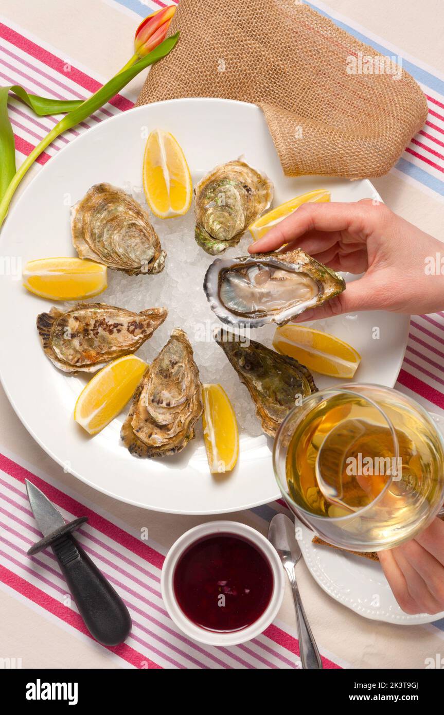 Eine Frau isst Austern und trinkt Weißwein in einem Restaurant Stockfoto