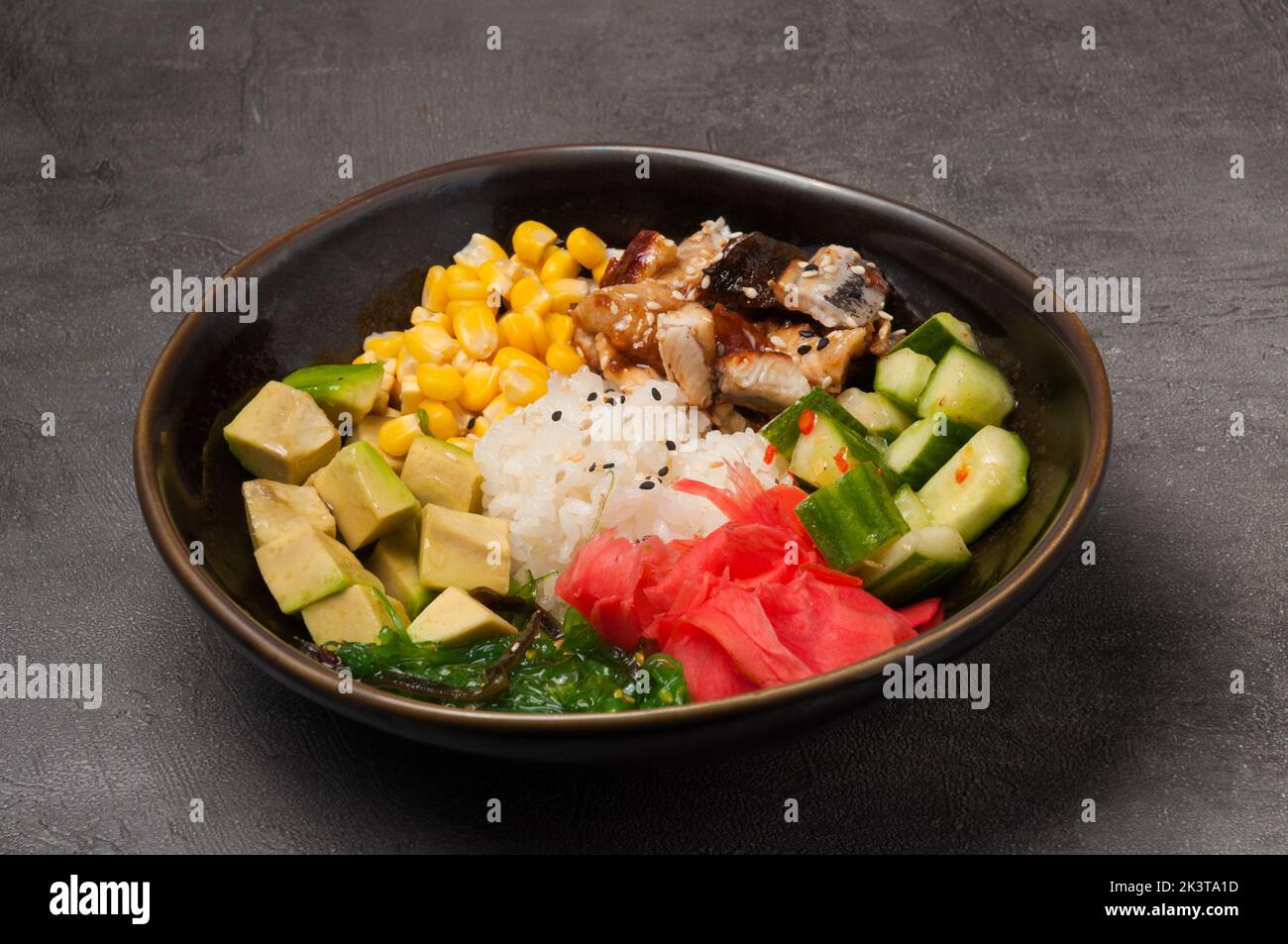 Schmackhafter Schnack mit Aal, Avocado, Gurke, Algen auf einem dunklen Teller Stockfoto