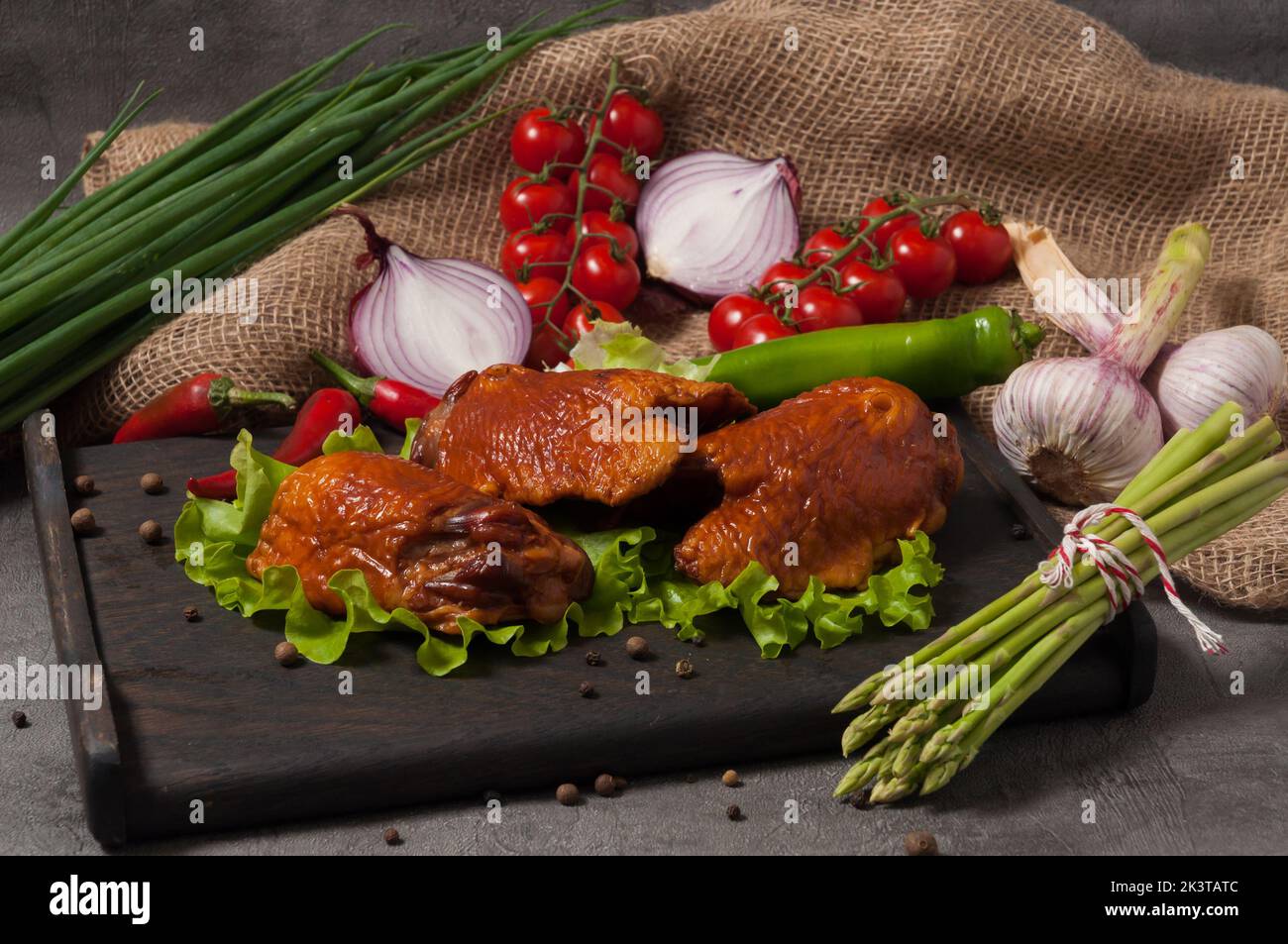 Leckere geräucherte Hühnerschenkel, garniert mit frischem Gemüse Stockfoto