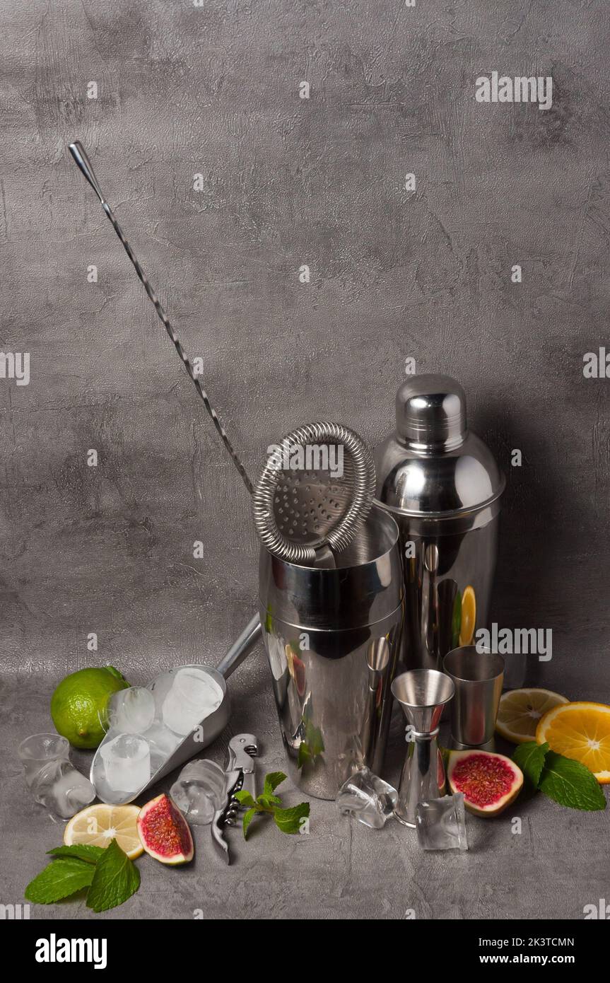 Set aus Barkeeper-Werkzeugen, die mit Früchten auf grauem Hintergrund verziert sind Stockfoto