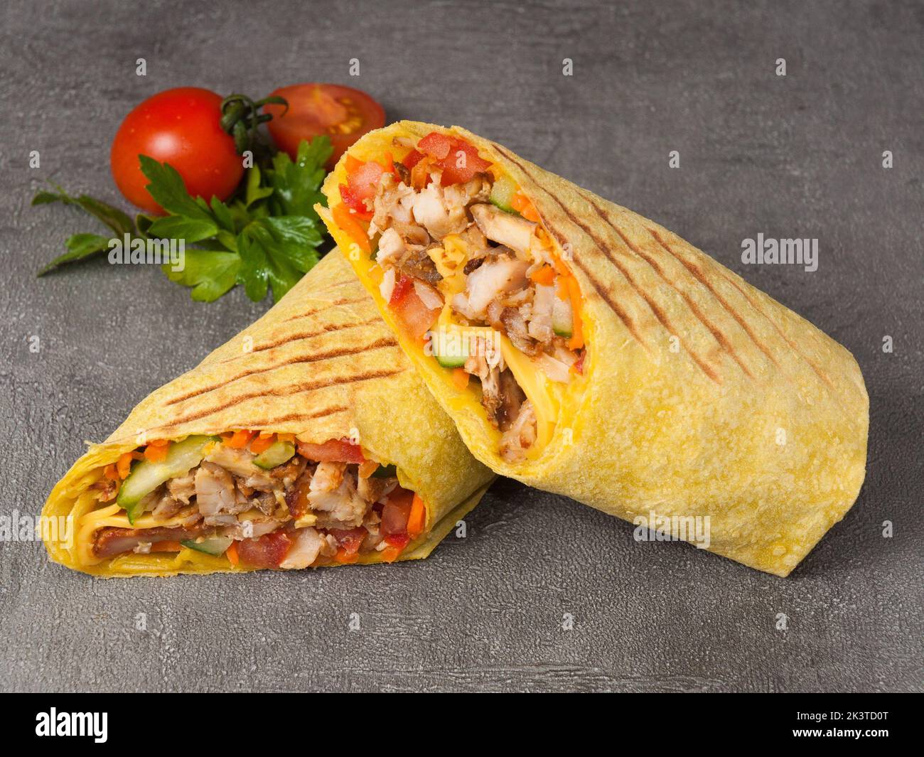 Leckeres Shawarma mit Huhn und Gemüse in Käse-Pita-Brot auf grauem Hintergrund. Nahaufnahme Stockfoto