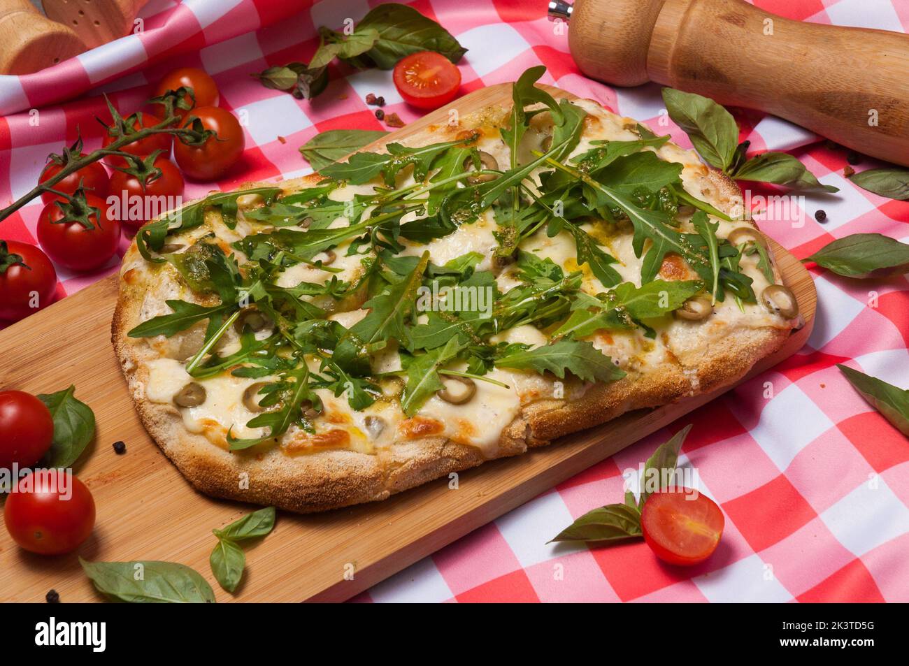 Leckere Pizza auf römischem Teig mit Käse, Oliven, Rucola und Pesto-Sauce Stockfoto