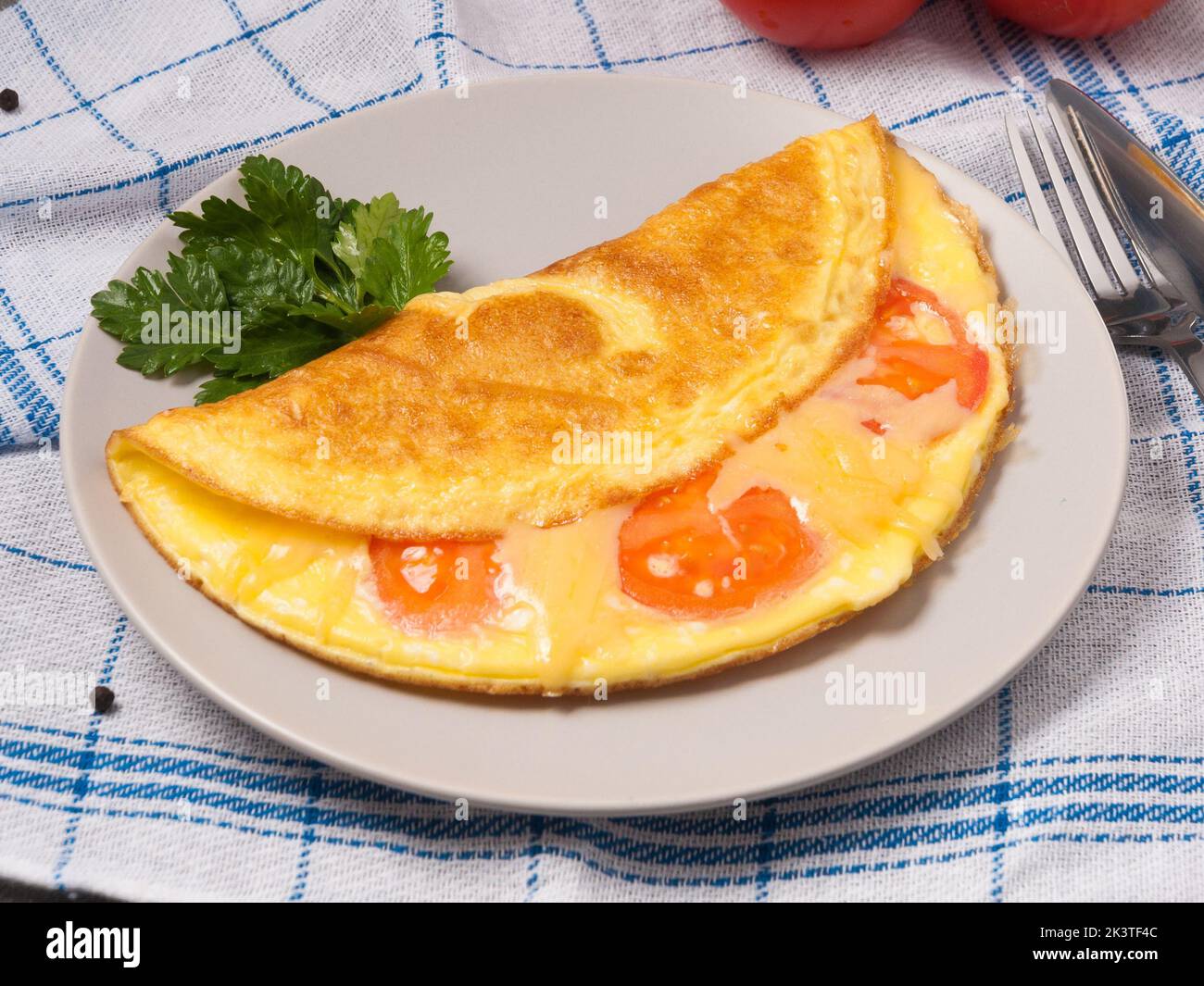 Leckeres Omelett mit Tomaten und Käse mit Kräutern verziert. Konzept: Frühstück Stockfoto