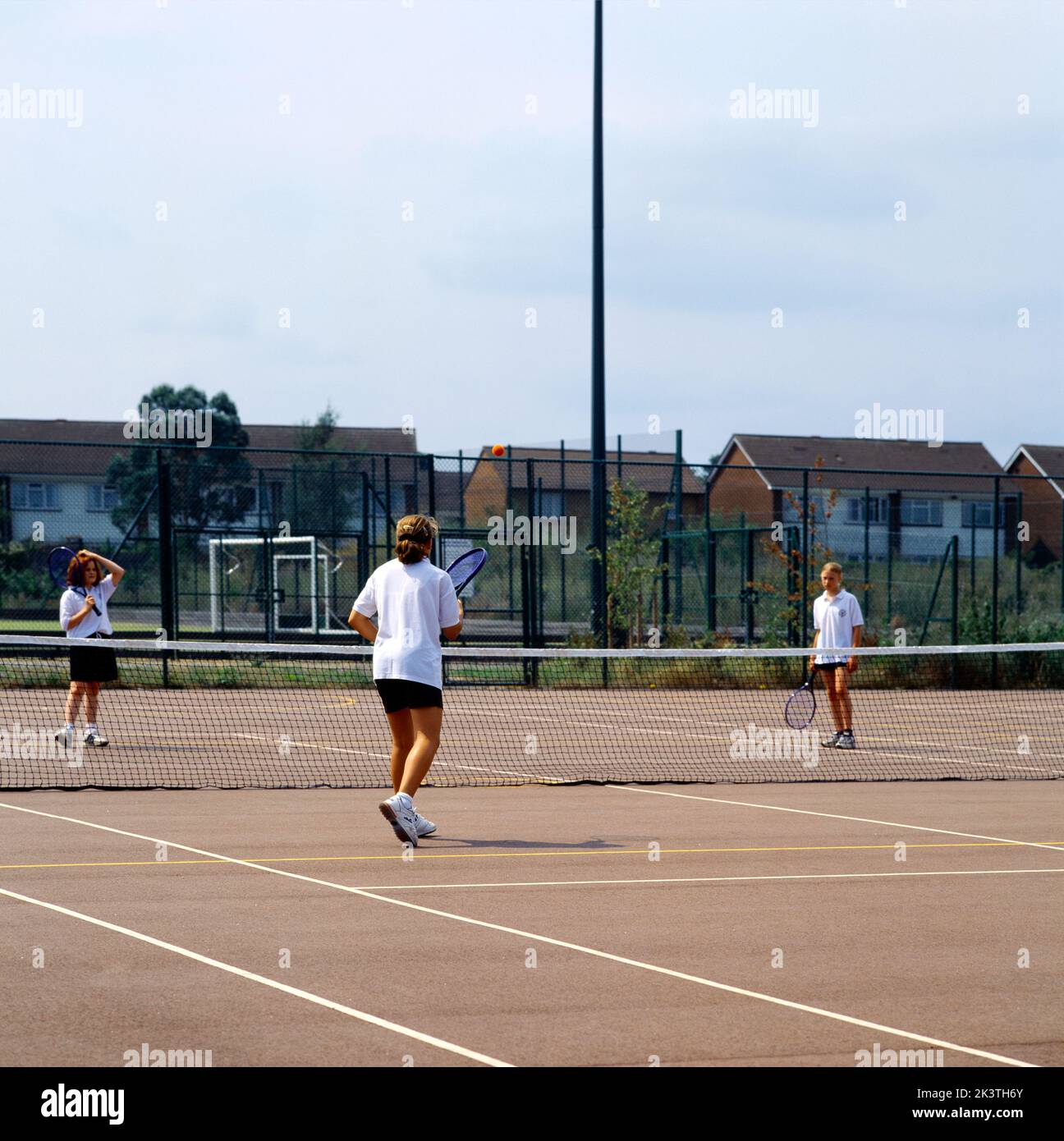 Teenager-Mädchen spielen Tennis in der Physical Education Class in High School England Stockfoto