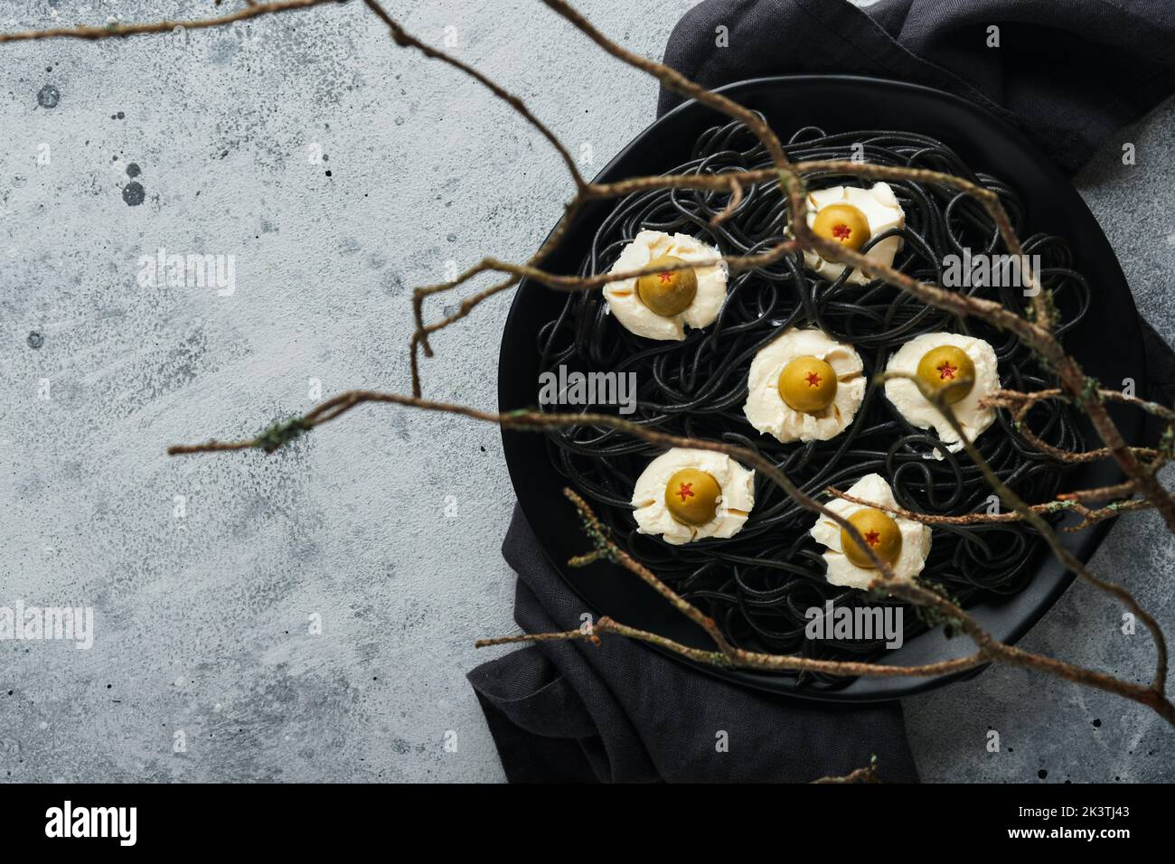 Halloween Party italienische schwarze Pasta dekoriert Horror Oliven wie Augen auf schwarzem Teller auf alten dunklen Tisch Hintergrund. Monster Gesicht von Pasta. Halloween Stockfoto