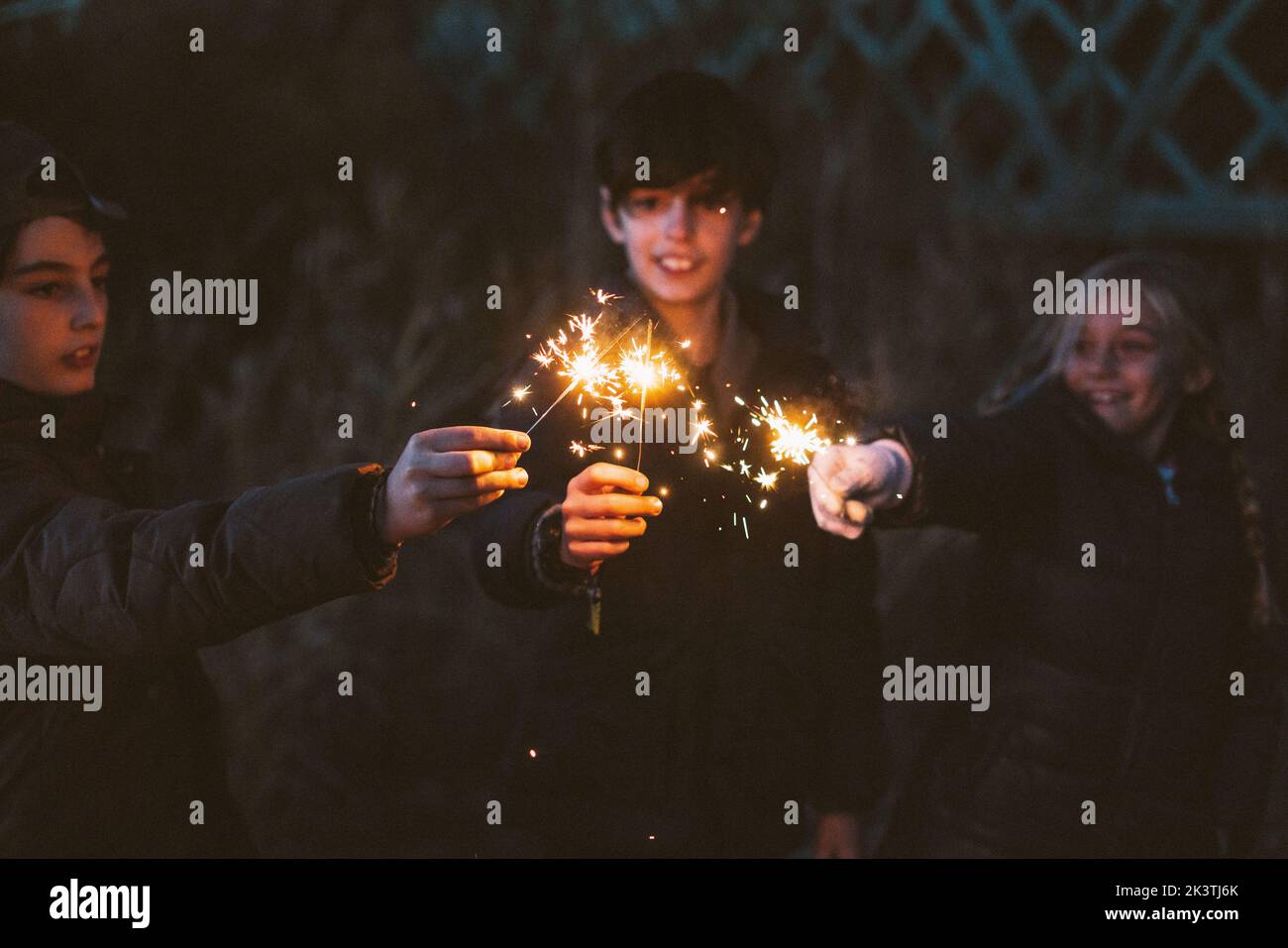 Gruppe von unerkennbaren verschwommenen jungen Jugendfreunden, die mit Funkeln auf dem Wald spielen Stockfoto