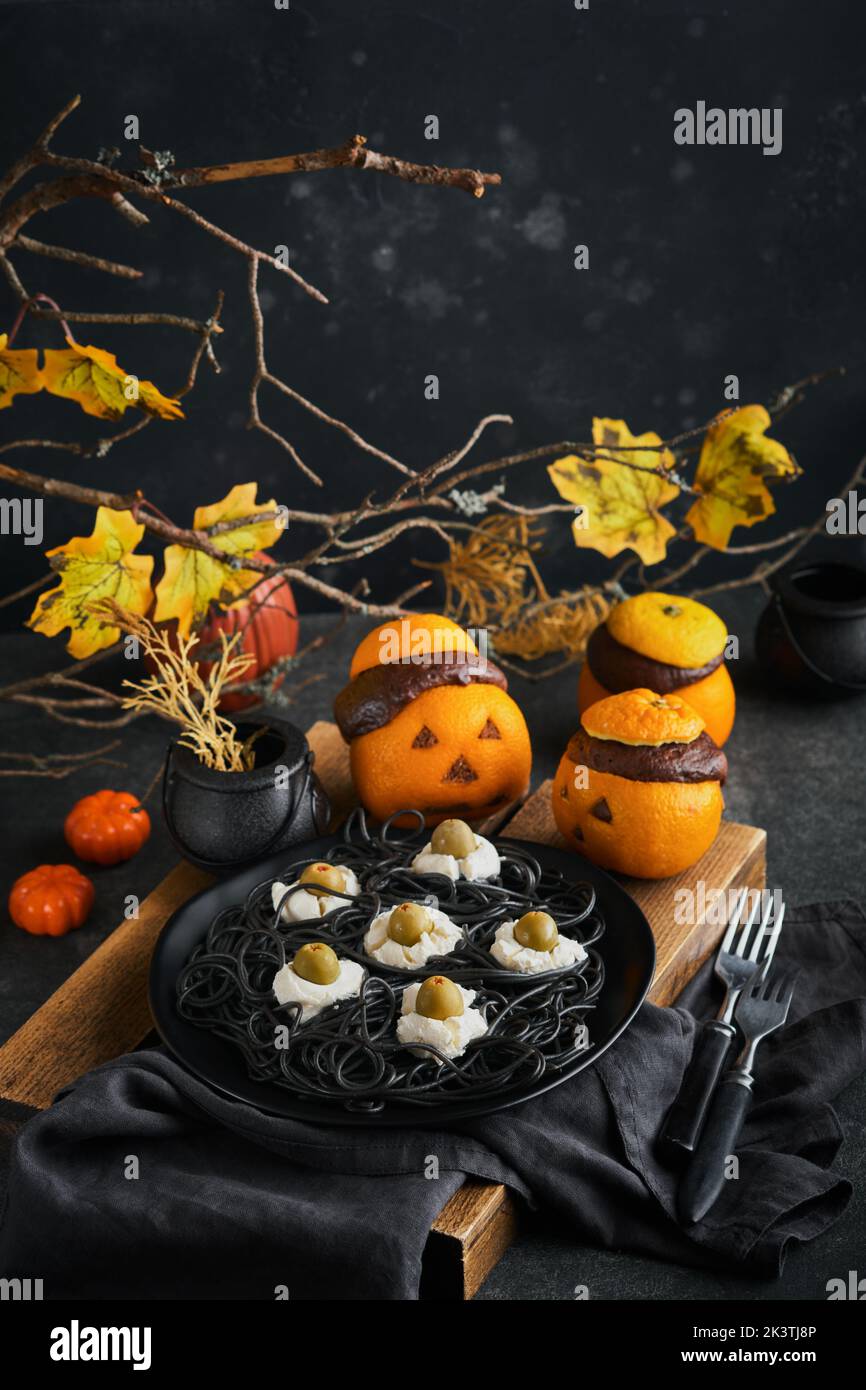 Halloween Party Jack-o-Laterne Schokolade orange Kuchen vor dem Hintergrund des alten Waldes, Äste und Blätter. Halloween-Food-Konzept. Süßigkeiten Stockfoto