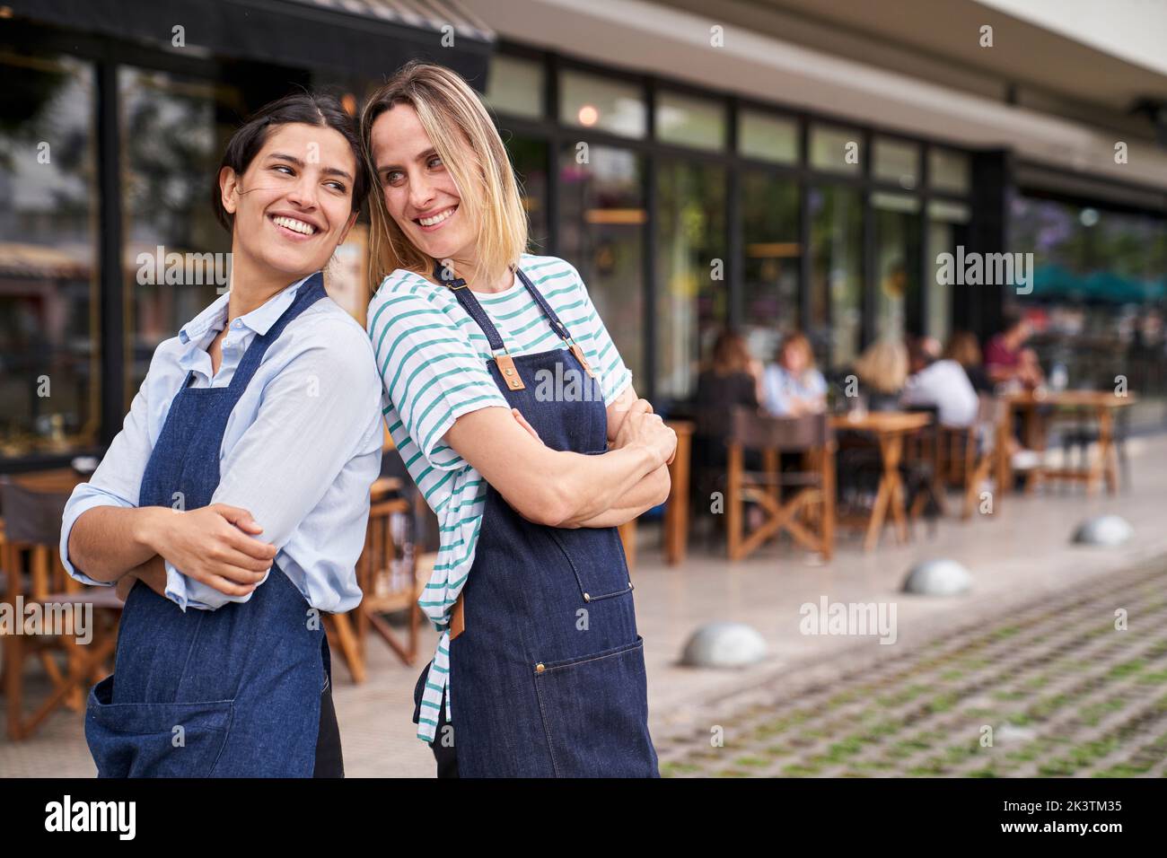 Porträt von zwei glücklichen weiblichen Restaurantbesitzern, die vor ihrem Restaurant posieren und Spaß haben Stockfoto
