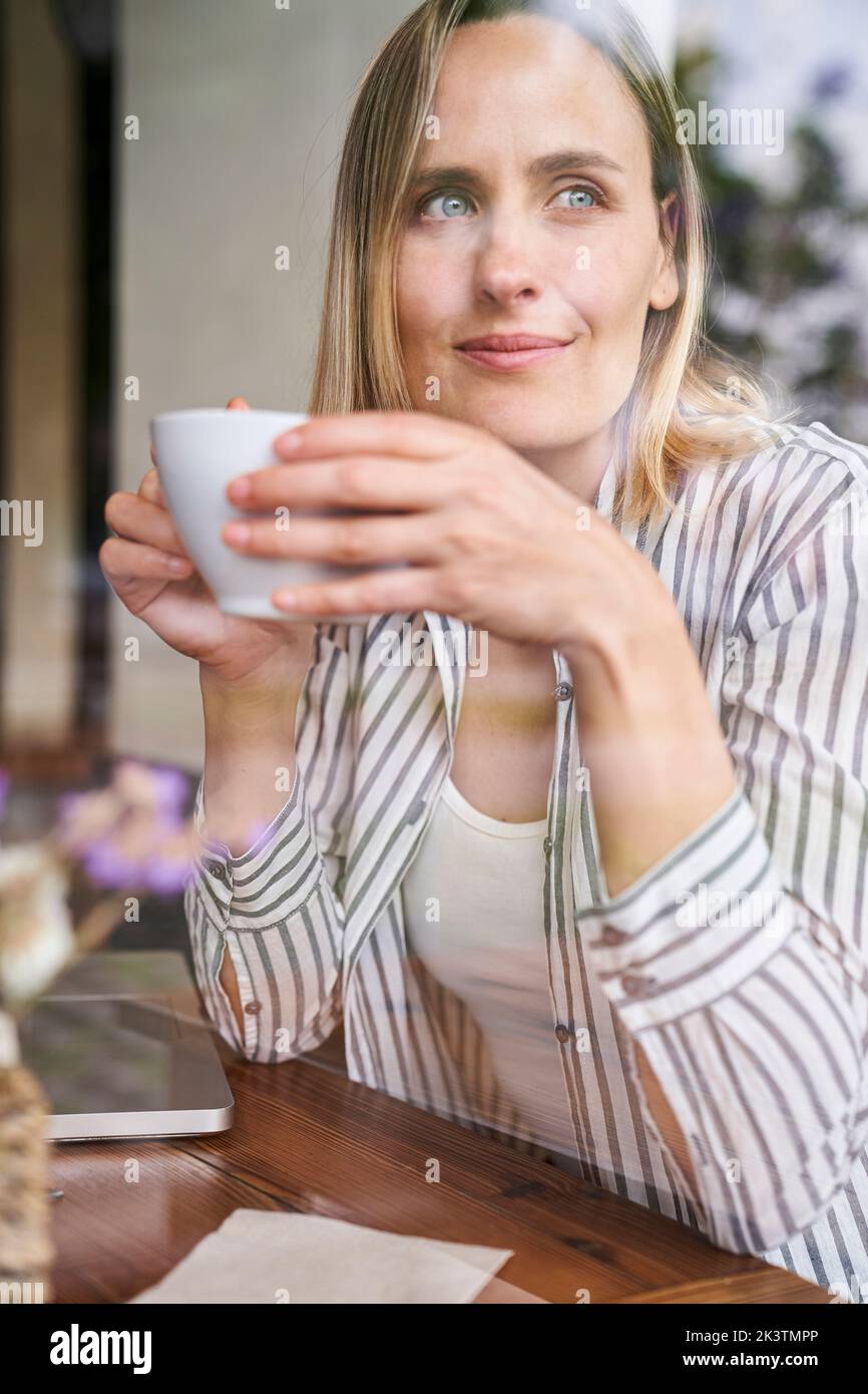 Mitten in der Aufnahme einer attraktiven Frau, die eine Tasse Kaffee im Café genießt Stockfoto