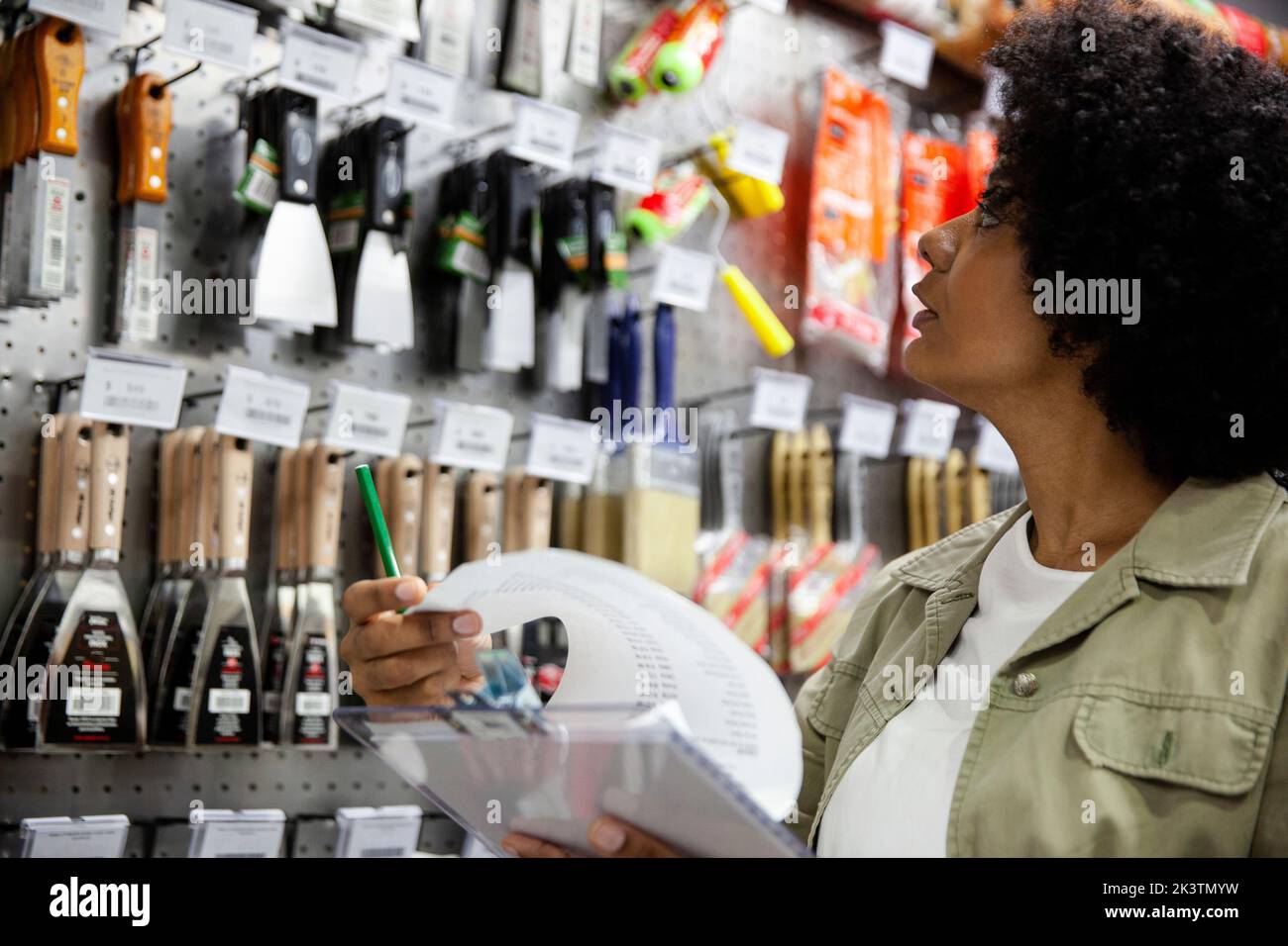 Afroamerikanisch weiblich Hardware Shop Besitzer Überprüfung Werkzeuge hängen auf Rack Stockfoto
