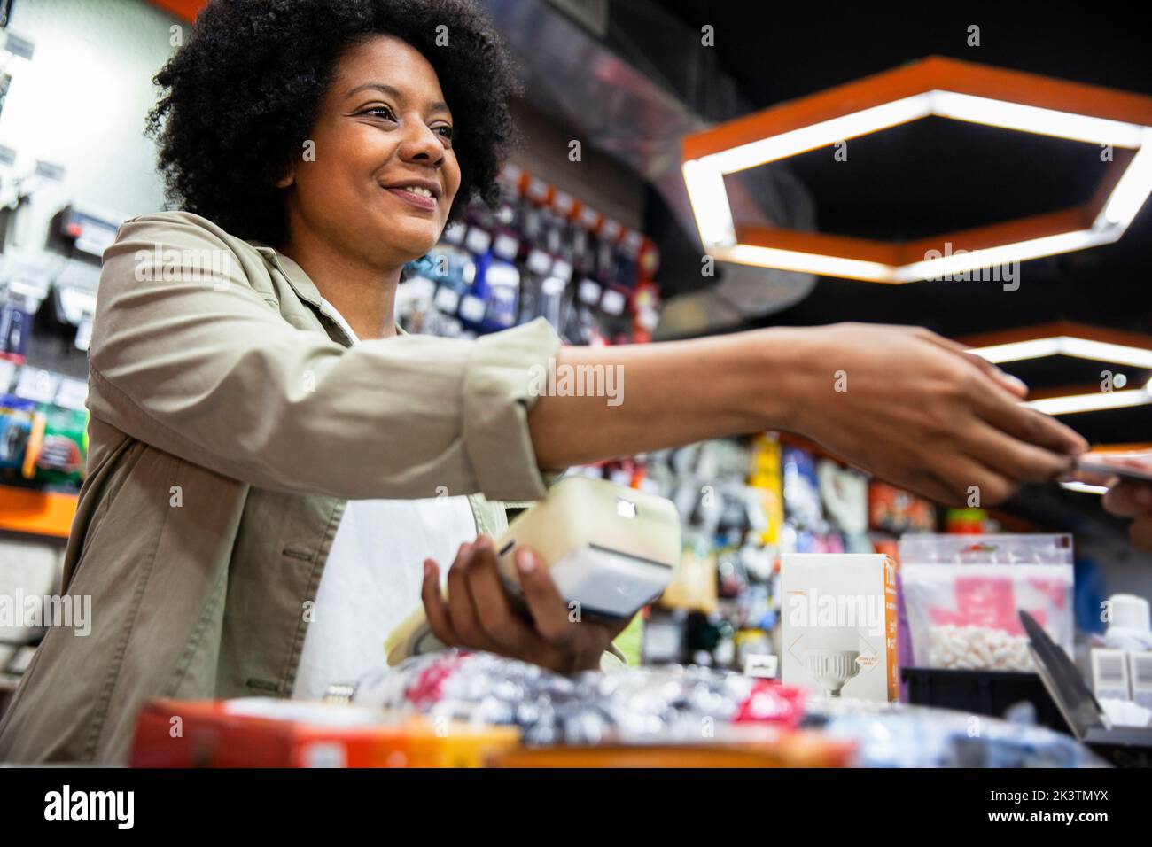Afroamerikanischer Hardware-Shop-Mitarbeiter, der dem Kunden eine Kreditkarte ablädt Stockfoto