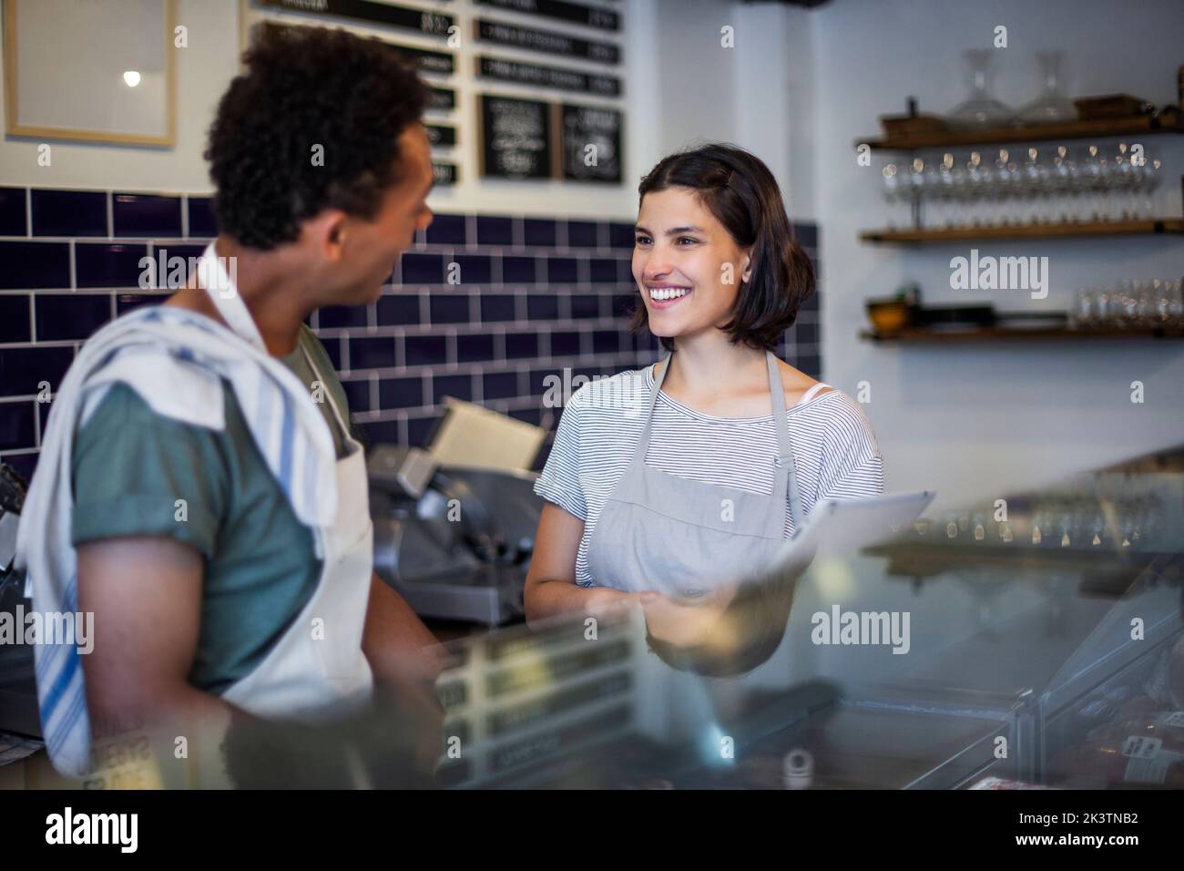 Mitarbeiter im Lebensmittelgeschäft reden, während sie hinter dem Tresen stehen Stockfoto