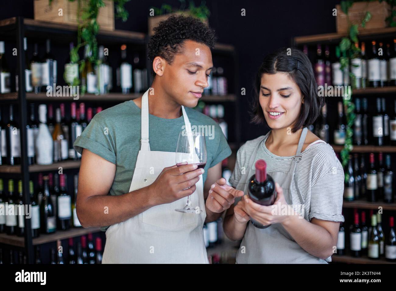 Mitarbeiter des Spirituosenladens halten eine Flasche und ein Glas Wein in der Hand Stockfoto
