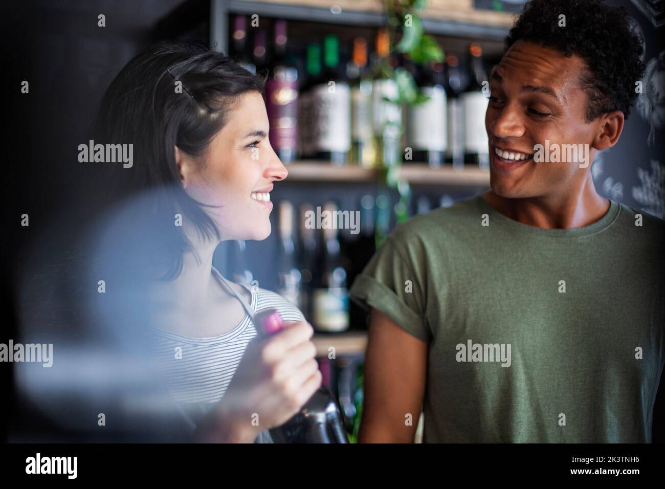 Angestellte im Spirituosengeschäft hält die Flasche, während sie mit dem Kunden spricht Stockfoto
