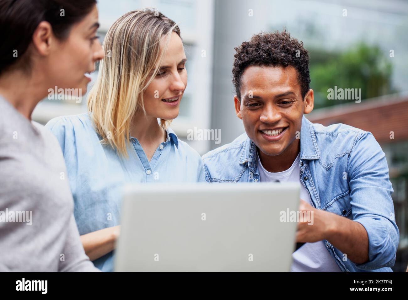 Kollegen aus kleinen Unternehmen diskutieren beim Betrastehen eines Laptops Stockfoto