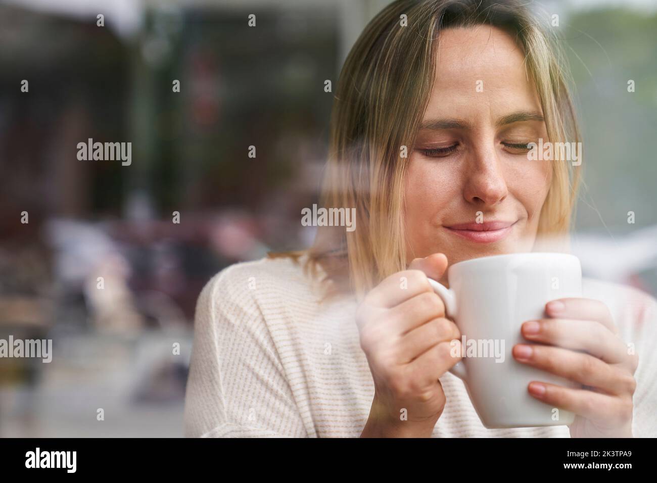 Porträt einer Frau mit geschlossenen Augen, die eine Tasse Kaffee genießt Stockfoto