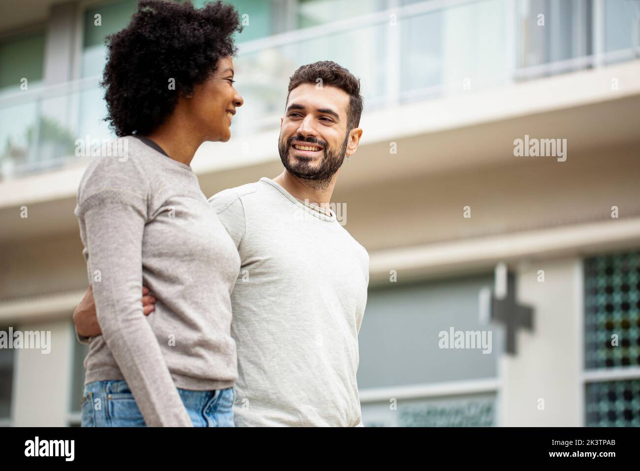 Glückliches junges erwachsenes Paar, das auf dem Bürgersteig läuft Stockfoto