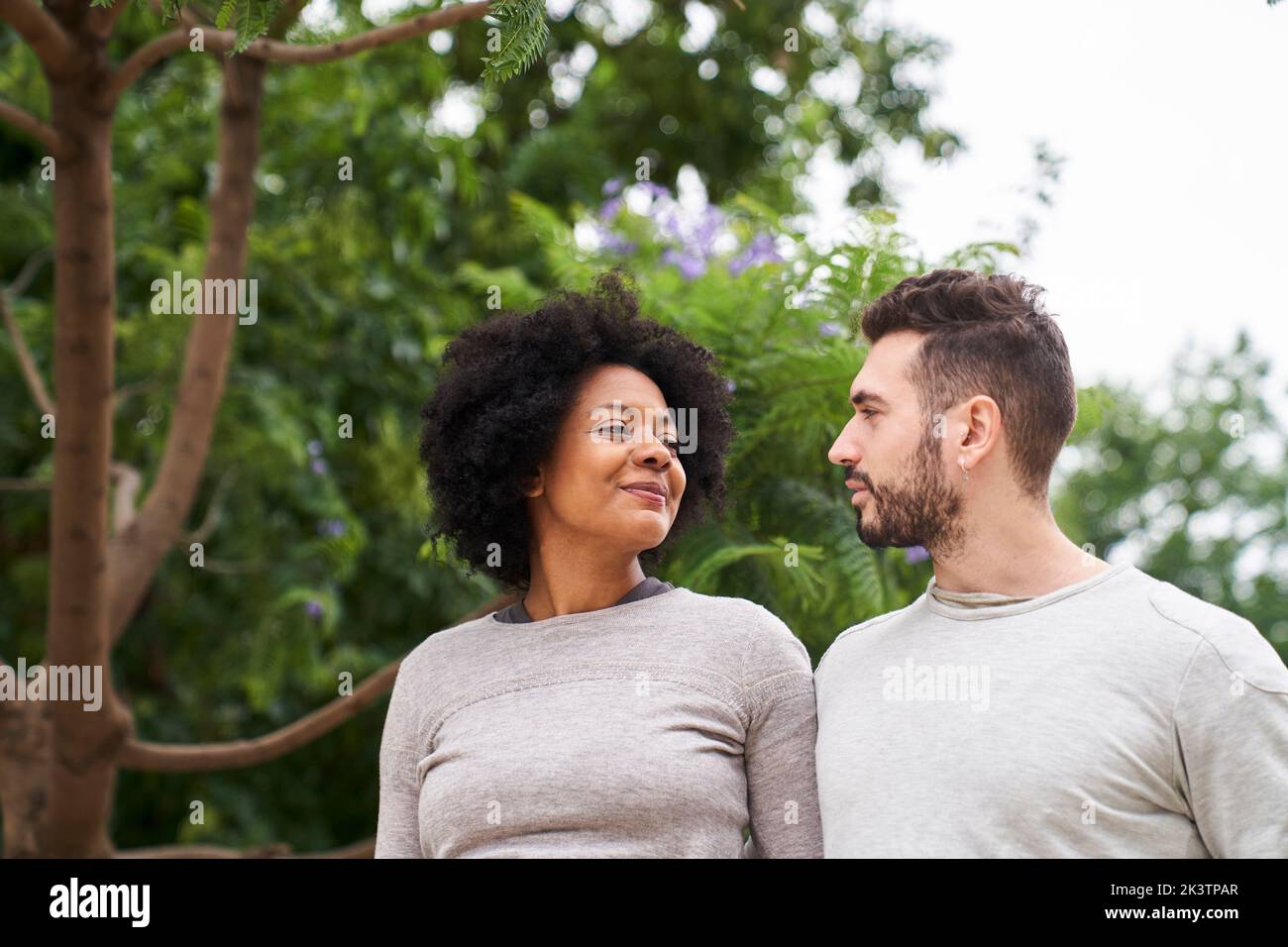 Mid-Shot-Porträt einer afroamerikanischen Frau und eines kaukasischen Mannes, der sich ansieht und eine gute Zeit im Freien hat Stockfoto