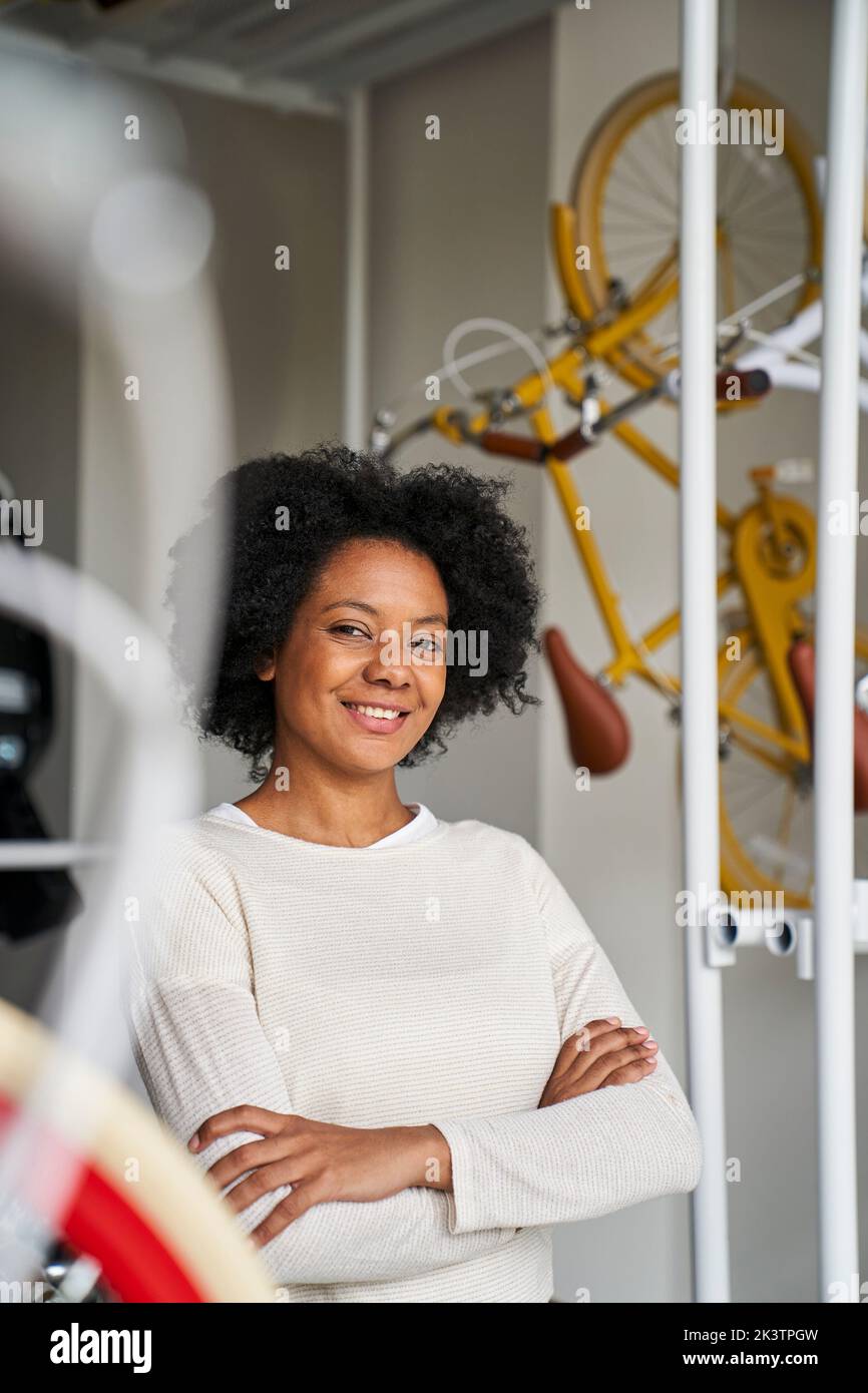 Porträt einer afroamerikanischen Unternehmerin, die in ihrem Fahrradladen posiert und von Fahrrädern umgeben ist Stockfoto