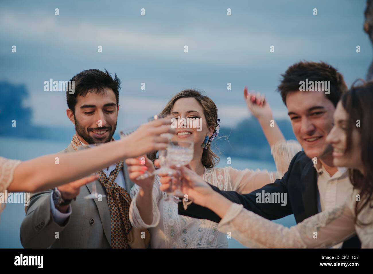 Junge glückliche Frauen und lächelnde Männer, die auf unscharfem Hintergrund eine Brille mit Getränken anklirren Stockfoto