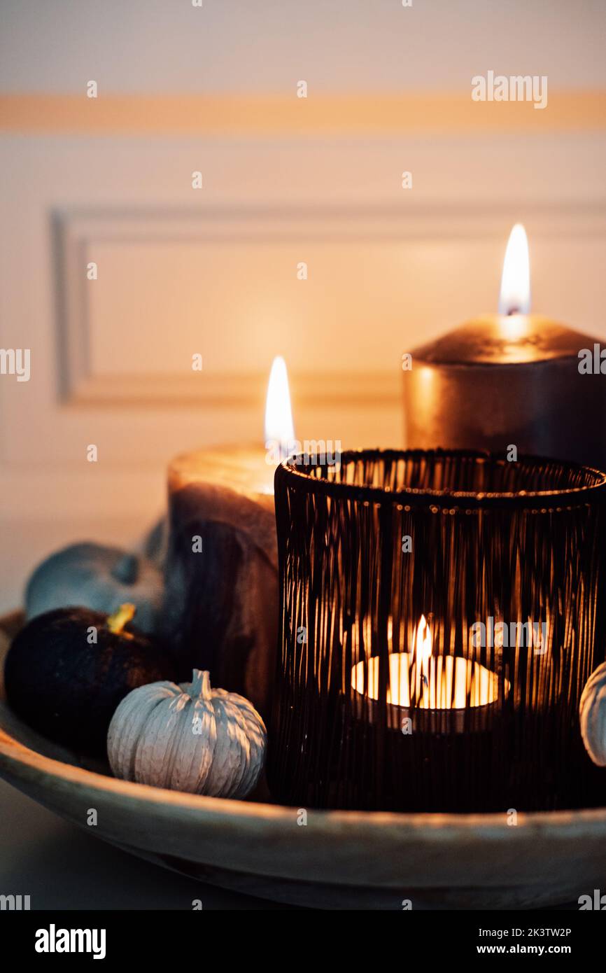 Halloween Komposition Kürbisse mit halloween schwarzen Duftkerzen und schwarzen Kürbissen in Holzplatte. Moderne Eleganz Halloween Zuhause drinnen Stockfoto